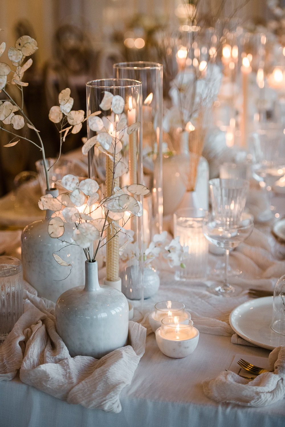 neutral palette wedding tablescape with lit golden candles and white vases and lunaria