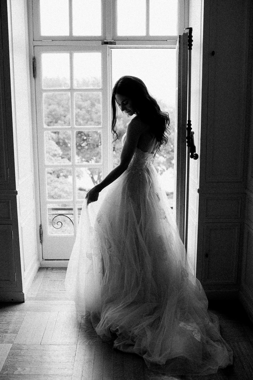 bride holding dress in front of full length window at Glen Manor House