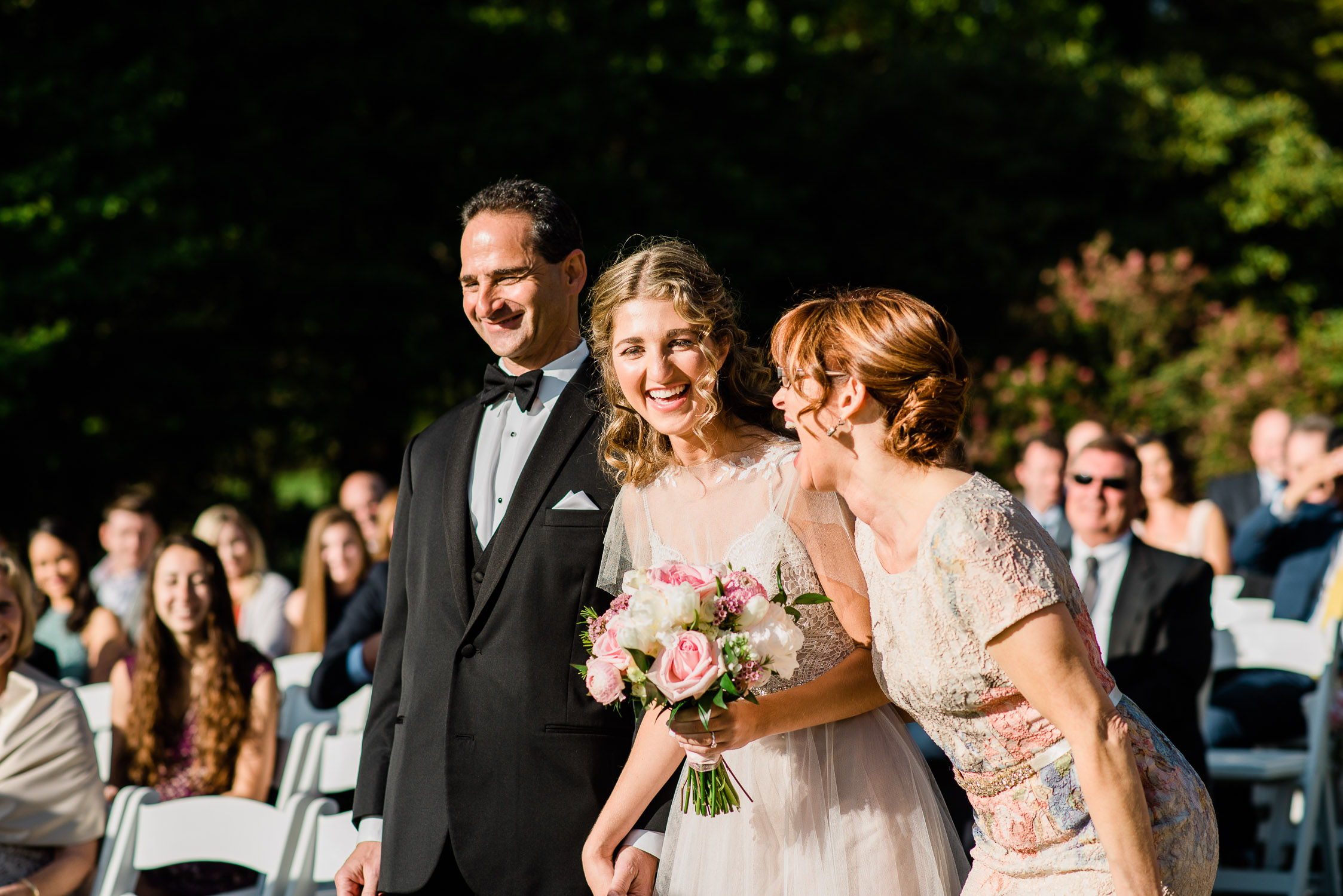 bride and mom and dad laughing walking down the ceremony aisle at Blithewold Mansion