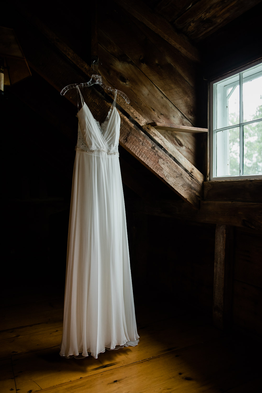 wedding dress hanging dramatically by window