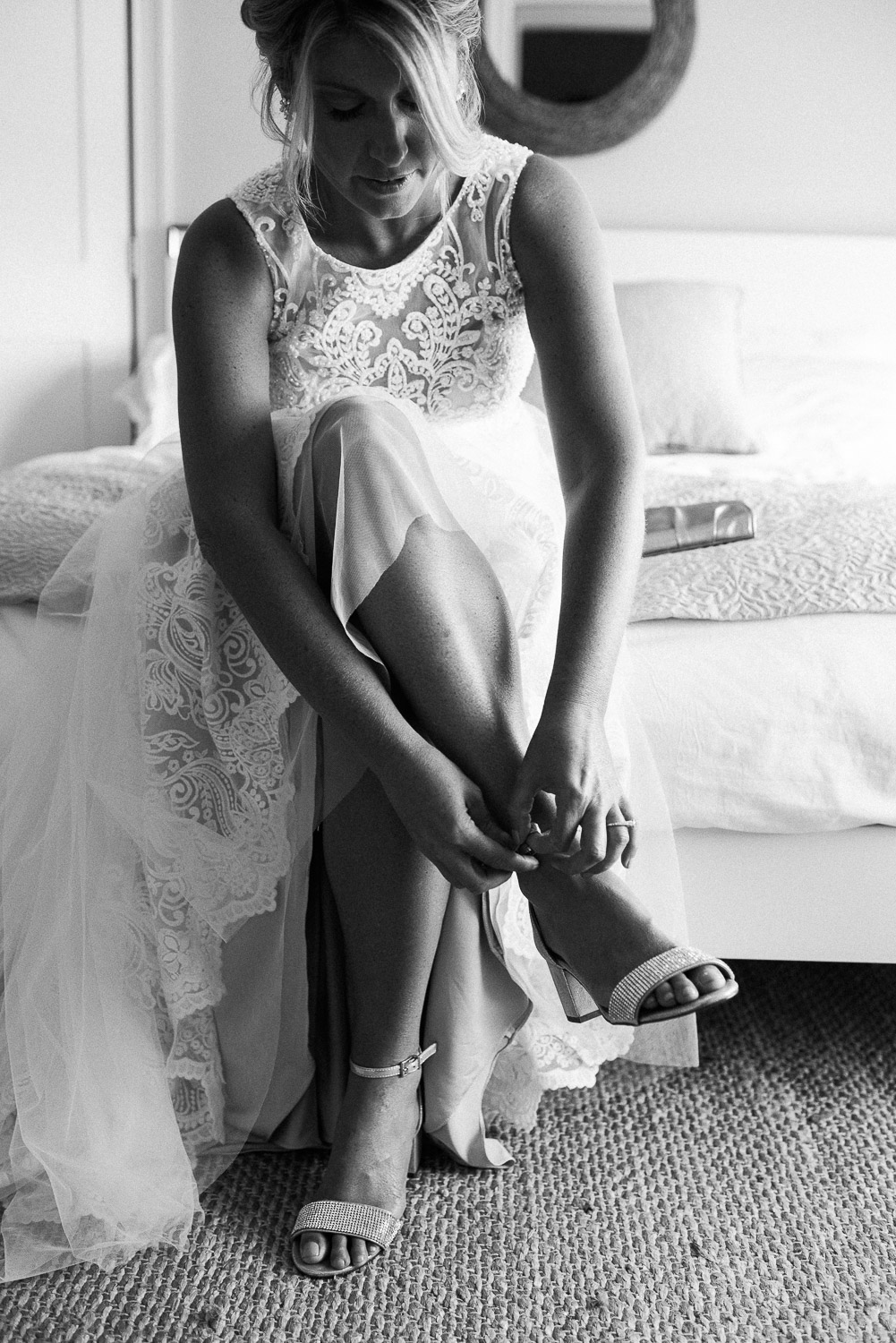 bride sitting down on bed buckling her shoe at the East Island Reserve Hotel Cottages