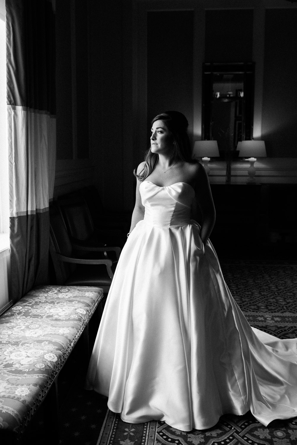 elegant bride standing by window with dramatic light at the Omni Mount Washington Resort