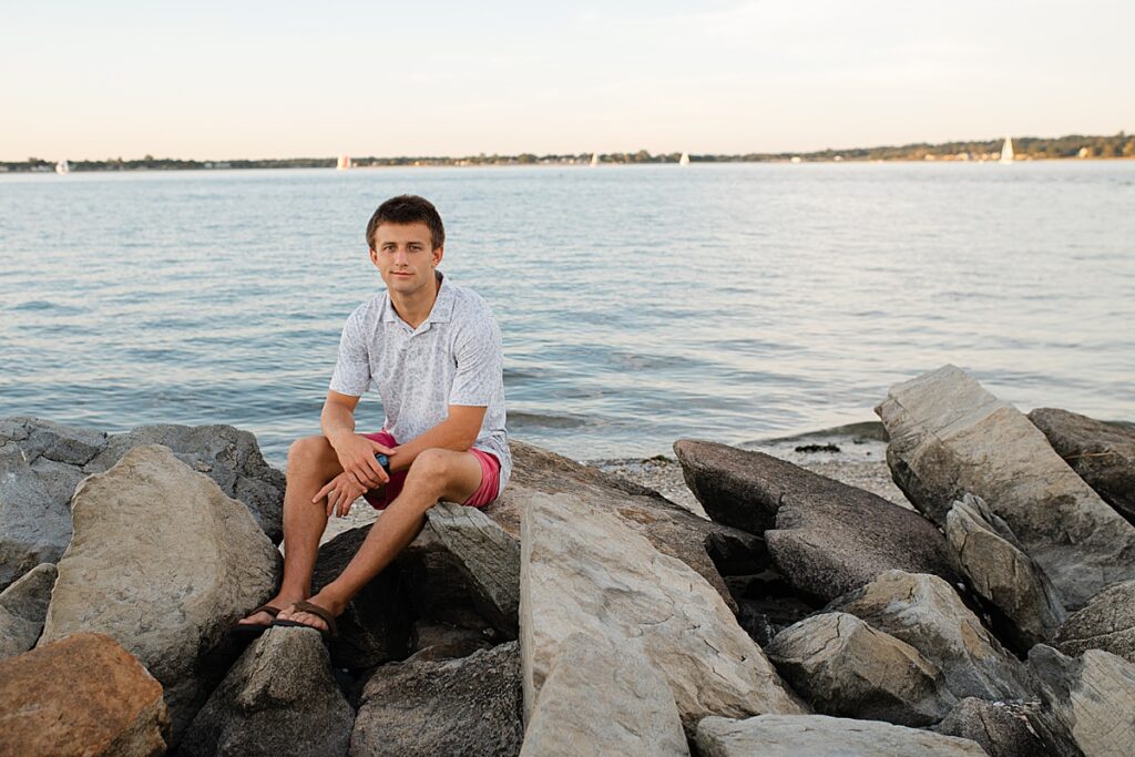 Senior boy sitting on rocks in front of the water