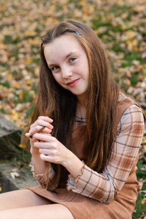 Rhode Island fall child portrait of a preteen girl with long hair sitting among autumn leaves