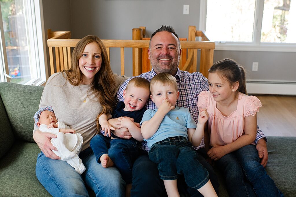 family of four portrait on couch at home with newborn
