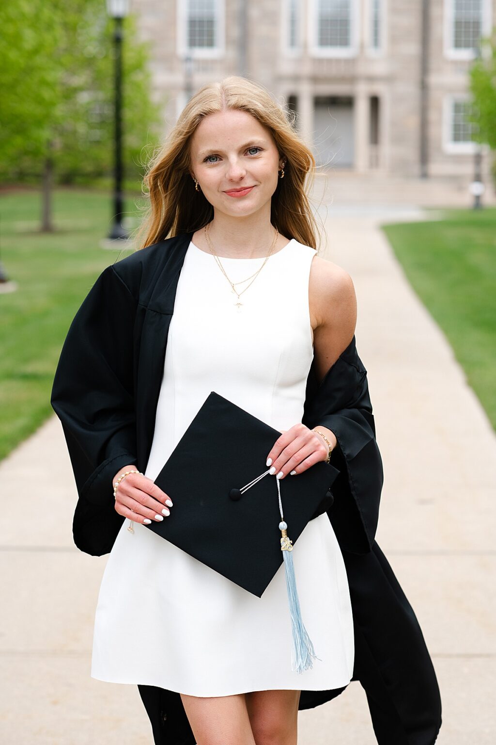URI grad holding cap in front of Greene Hall