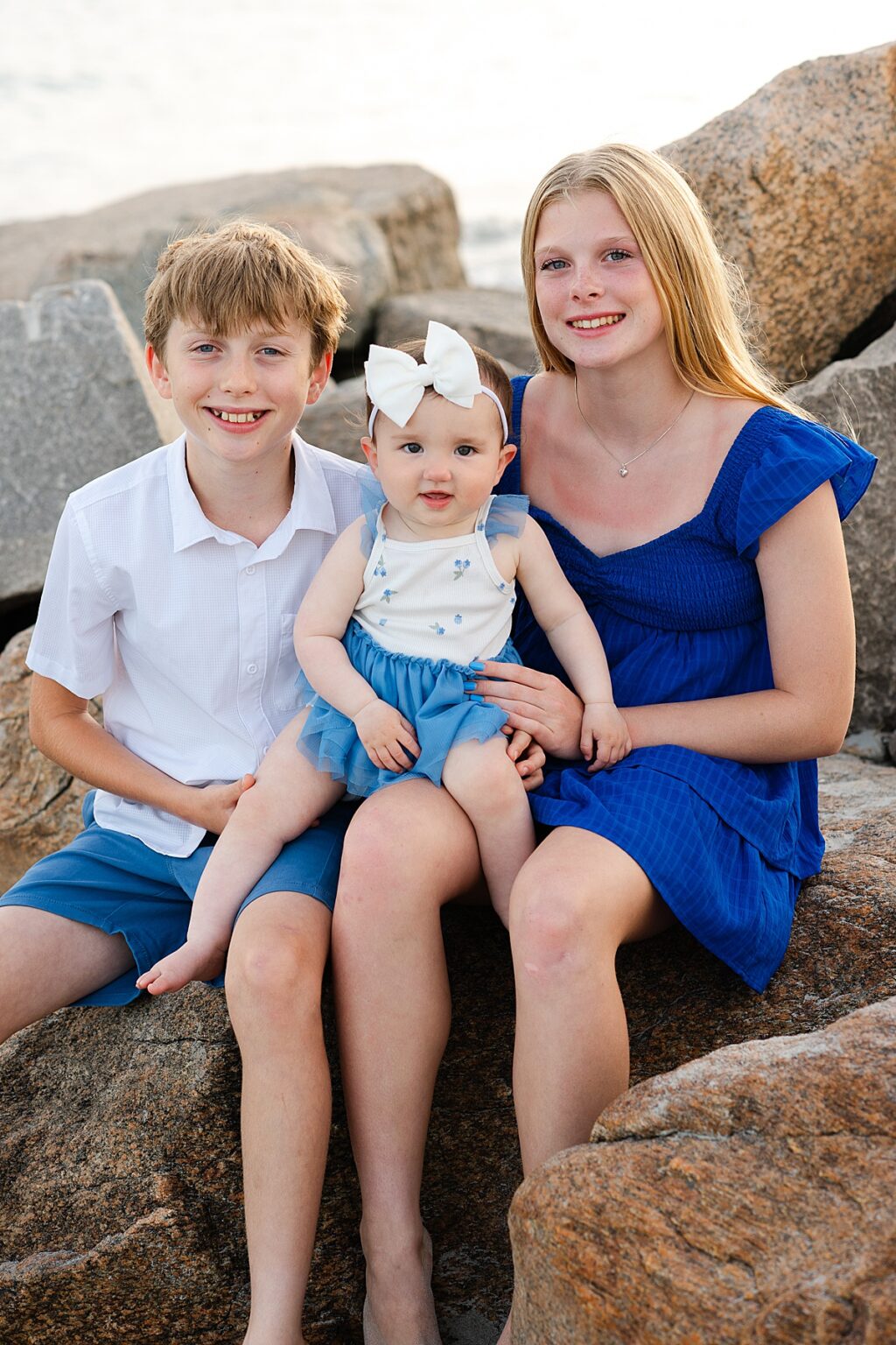 Grandchildren sitting together on seaside rocks